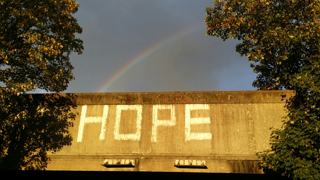 Hope grafittied on a wall with rainbow in the sky